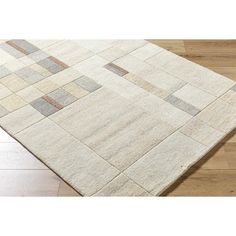 a white rug with brown and grey squares on top of wooden flooring next to hardwood floors