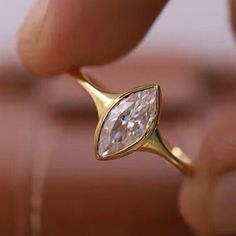 a close up of a person holding a ring with a pear shaped diamond in it