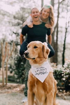 a man and woman are holding their dog in the air while he is wearing a bandana