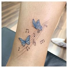 two blue butterflies with musical notes on their wings are shown in this tattoo by the artist