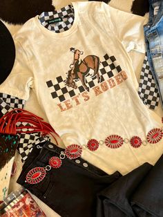 Saddle up in style with this Let's Rodeo tee! Made with 100% cotton, this cream-colored shirt features a checkered horse and cowboy graphic, perfect for any cowboy or cowgirl. Whether you're at a rodeo or just want to add some western flair to your wardrobe, this tee is sure to be a hit. Giddy up! **Checkered long sleeve mesh top sold separately** Cowboy Graphic, Christmas Delivery, Rodeo, Mesh Top, Saddle, In Style, Colorful Shirts, Cowboy, Mesh