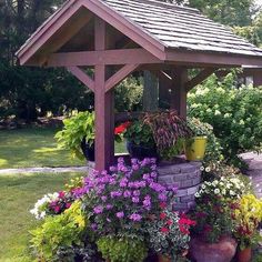 a gazebo with potted plants and flowers around it