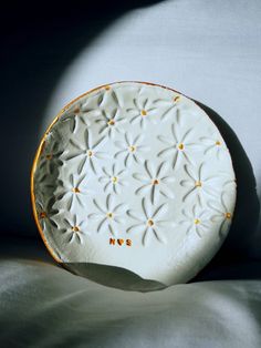 a white plate sitting on top of a bed next to a shadow from the wall