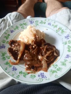 a white plate topped with meat and gravy covered in gravy on top of mashed potatoes