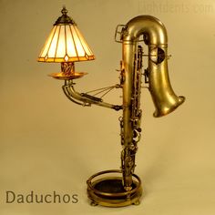 an old brass saxophone lamp with a glass shade on it's head and neck