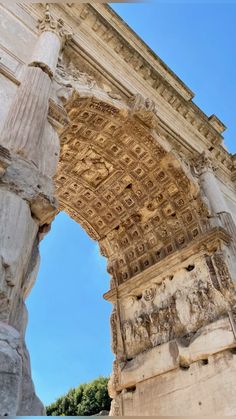 an old stone arch with carvings on the side and blue sky in the back ground