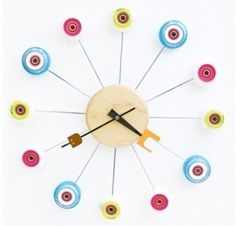 a clock made out of different colored spools on a white surface with black hands