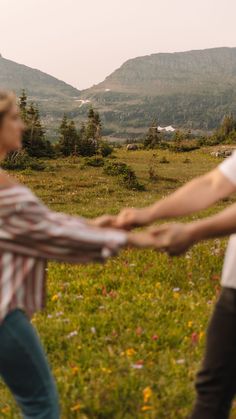 two people holding hands in the middle of a field