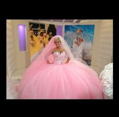 a woman in a pink wedding dress sitting on a bed