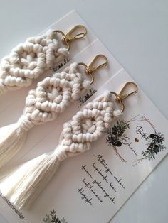 three white tassels with gold hooks are on top of a piece of paper