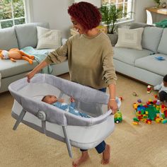 a woman is holding the baby's hand in her crib while playing with toys