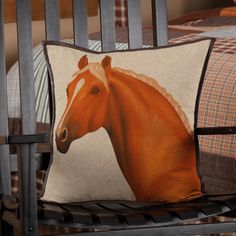 a brown horse pillow sitting on top of a wooden chair next to a plaid bedspread