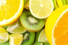 sliced kiwis, oranges and lemons on a green cutting board together