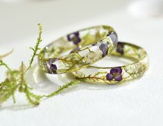 A delicate resin ring with dried Sweet Alyssum flowers and moss. This dainty and sweet ring is perfect for the nature lover in you or someone special, serving as an ideal promise ring or purity ring. The smooth surface of the ring showcases a translucent resin that captures the essence of a serene forest glade. Embedded within this enchanting piece are carefully placed accents of dried moss and delicate Sweet Alyssum flowers, adding a touch of whimsy and natural charm. Whether you're expressing Dried Flowers Resin, Alyssum Flowers, Forest Glade, Sweet Alyssum, Serene Forest, Flowers Ring, Flowers Resin, Flower Resin Jewelry, Purity Ring