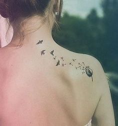 the back of a woman's shoulder with birds on it and stars in the sky