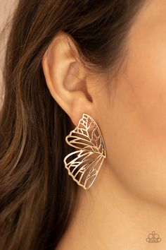 a close up of a woman's ear wearing gold earrings with an intricate design