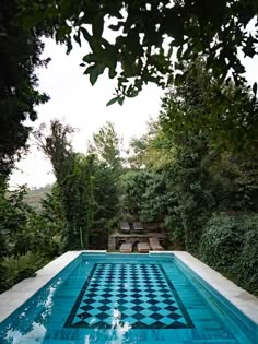 an empty swimming pool surrounded by greenery and blue skies with clouds in the sky