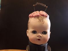 a baby doll head with pins in it's hair sitting on top of a table