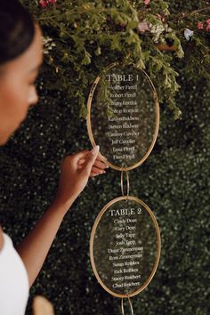 a woman is holding up a table number holder with the names of her wedding guests