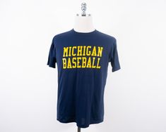 "Vintage wolverines baseball shirt in fairly good condition, area of discoloration at bottom of shirt Made in U.S.A. Size: Tagged L, measures closest to a modern day M (please see measurements) Measurements taken with garment laid flat. Shoulder: 18.25\" Chest: 20.5\" Length: 26\" Sleeve: 8\" Material: 50% Cotton 50% Polyester Label: Jerzees Please message me with questions or for additional photos." Collegiate Cotton Baseball Jersey For Fans, Varsity Cotton Baseball Jersey For Fan Gear, Cotton Varsity Baseball Jersey For Fan Gear, Cotton Baseball Jersey With Team Logo, Cotton Baseball Jersey For Fans, Cotton Baseball Jersey With Short Sleeves For Fans, Cotton Short Sleeve Baseball Jersey For Fans, Crew Neck Baseball Fan Jersey, Collegiate Style Short Sleeve Baseball Jersey