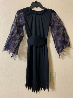 a black dress with purple lace on the sleeves and neck, hanging from a hanger