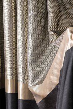 closeup of curtains with black and gold trims on the curtain rod ends in front of them