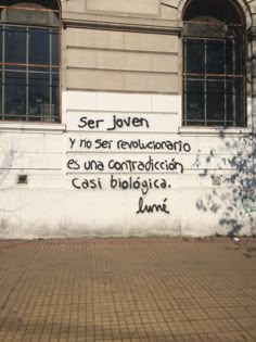 graffiti written on the side of a building in latin writing is shown below an arched window