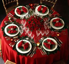 a table set for christmas dinner with red napkins and silverware