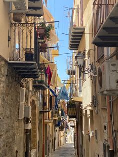 an alleyway with several balconies and clothes hanging from the balconys on either side