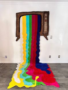 a multicolored rug is on the floor in front of a wall with a television