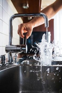 someone is washing their hands in the kitchen sink with water splashing from the faucet