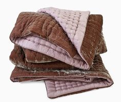 three blankets stacked on top of each other in brown and pink colors, with one blanket folded over the edge