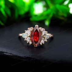 an oval shaped red stone surrounded by small white stones on top of a black surface