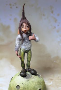 a doll is standing on top of a green ball with an odd head and legs