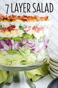 a layered salad with lettuce, tomatoes, onions and other ingredients in a glass dish