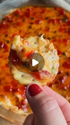 a hand holding up a piece of pizza with cheese and pepperoni on it in front of a pan