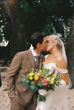 a bride and groom kissing in front of trees