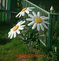 two fake white flowers in front of a green fence