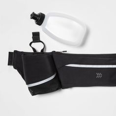 the waist pack is next to a bottle of water and an armband on a white surface