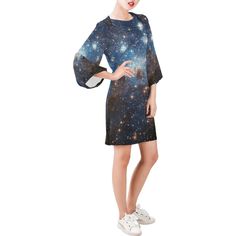 a woman standing in front of a white background wearing a dress with stars on it