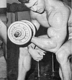 an old photo of a man lifting a barbell