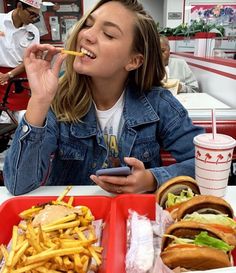 a woman sitting at a table with two trays of food