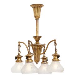 an antique brass chandelier with three glass shades