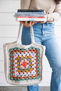 a woman is holding a crocheted bag and books