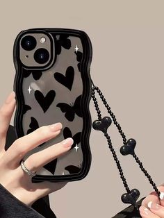 a woman holding up an iphone case with hearts on it and black beads attached to the back