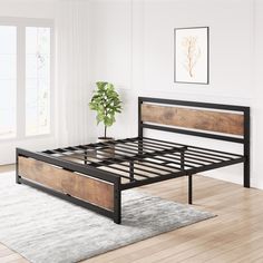 a bed frame with wooden slats in a white room next to a potted plant