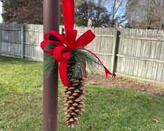 a pine cone tied to a pole with a red bow