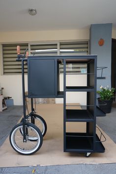 a black bike is parked in front of a bookcase and shelves on the floor