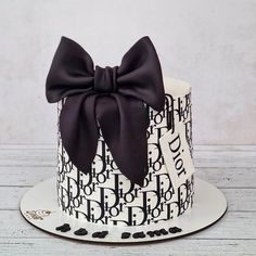 a black and white cake with a large bow on it's top, sitting on a plate