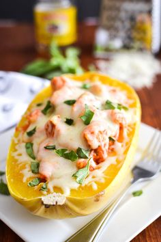 a stuffed yellow squash with shrimp and cheese on the top is sitting on a white plate